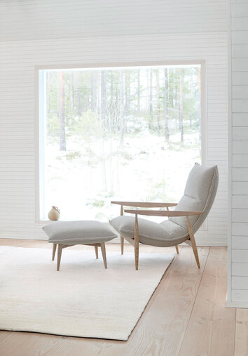 Miljöbild på fåtöljen Tao, med tillhörande fotpall. Fåtöljen är klädd i tyget Orsetto 12, med stomme i ek. 