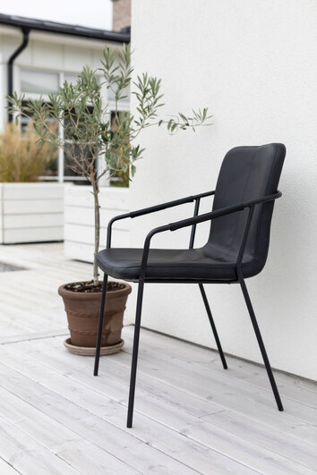 Evo Stol i svart PU i utomhusmiljö vid husfasad bredvid en krukväxt