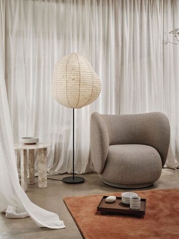 Taula Sidobord i utförandet Sand bredvid en golvlampa och en fåtölj