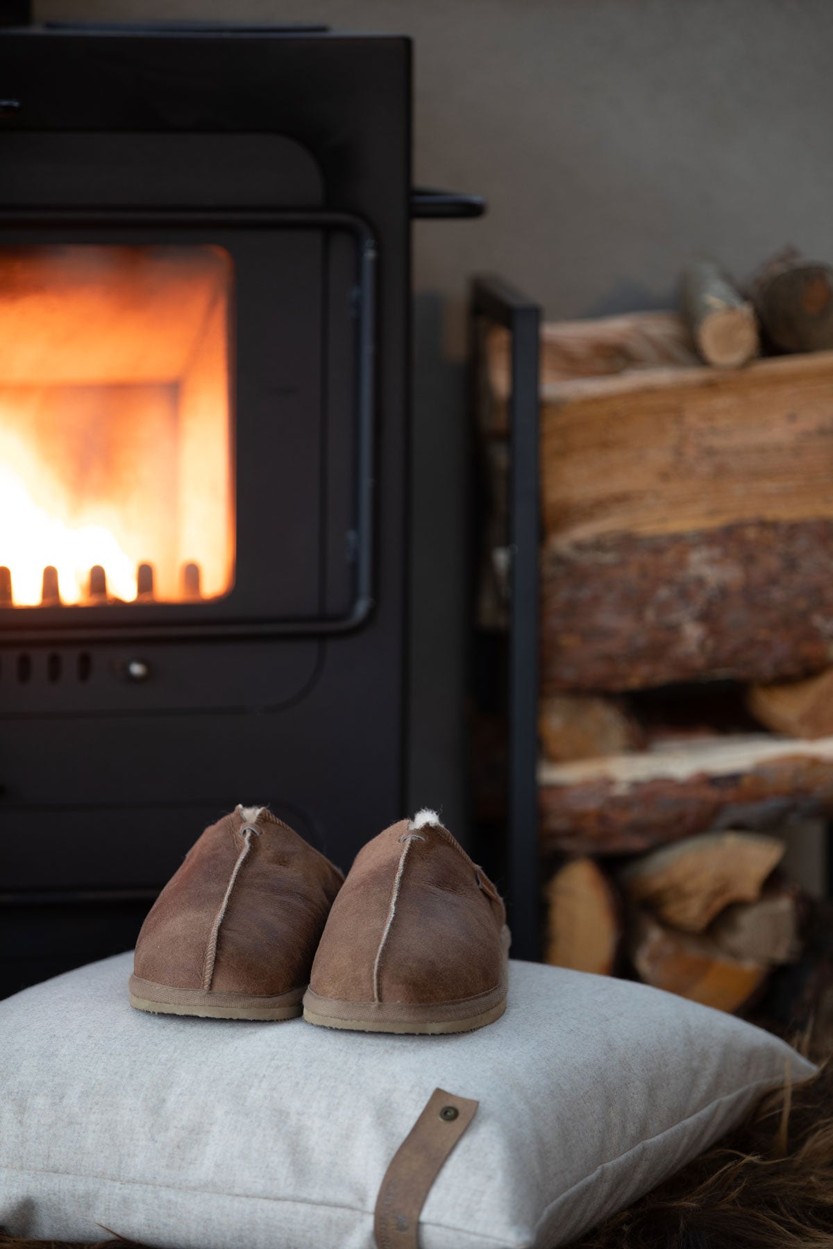 Hugo Fårskinnstofflor Cognac framför braskamin