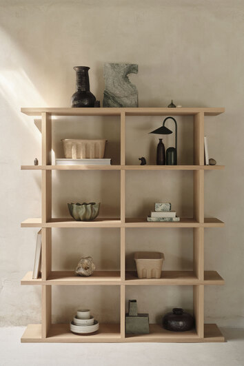 Kona 2x4 i färgen Natural ståendes mot vägg fylld med dekorationer.