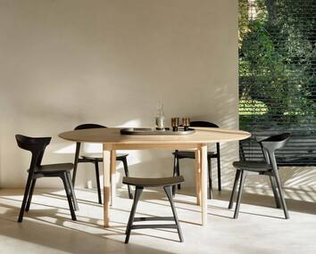 Bok Stol i svartlackad ek runt matbord vid fönster som vetter ut mot grönska