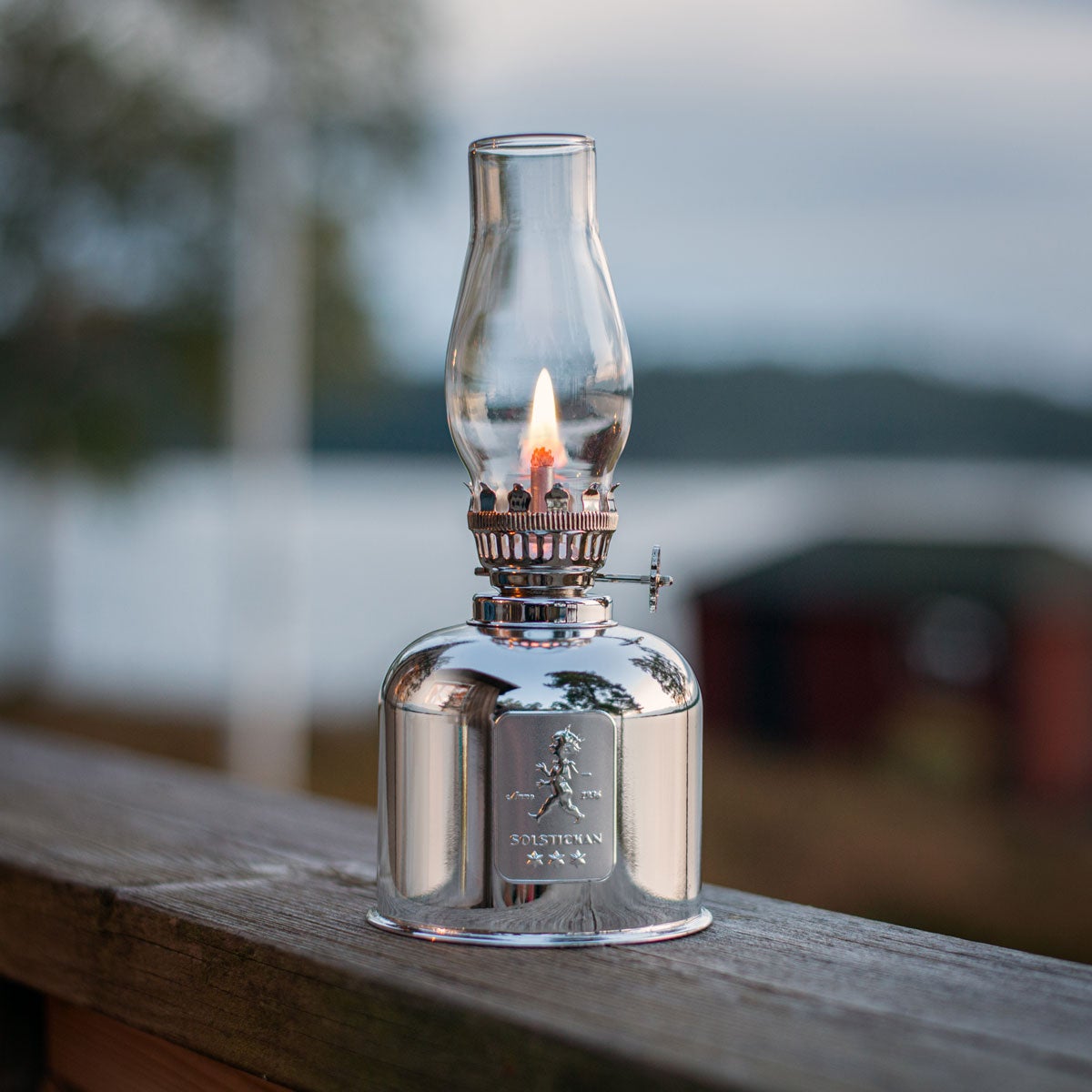 Fotogenlampa i silver ståendes på ett trappräcke utomhus 