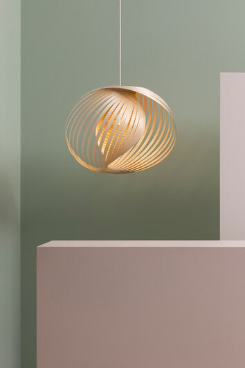 Adilo 8200 Taklampa i björk som hänger mot en ljusgrön vägg