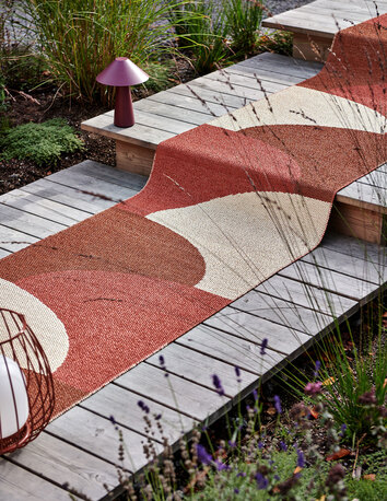 Hill Gångmatta i färgen Brick/Rust på trappa i trä utomhus