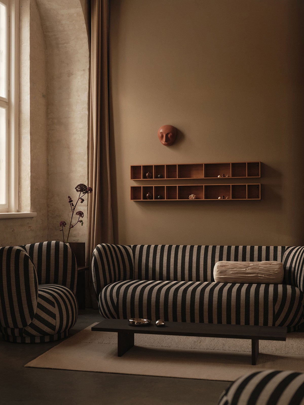 Kompliment Matta i färgen Off-White under en randig soffgrupp i ett vardagsrum