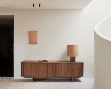 Pillar Sideboard i bredden 220 centimeter dekorerat med en bok och en bordslampa