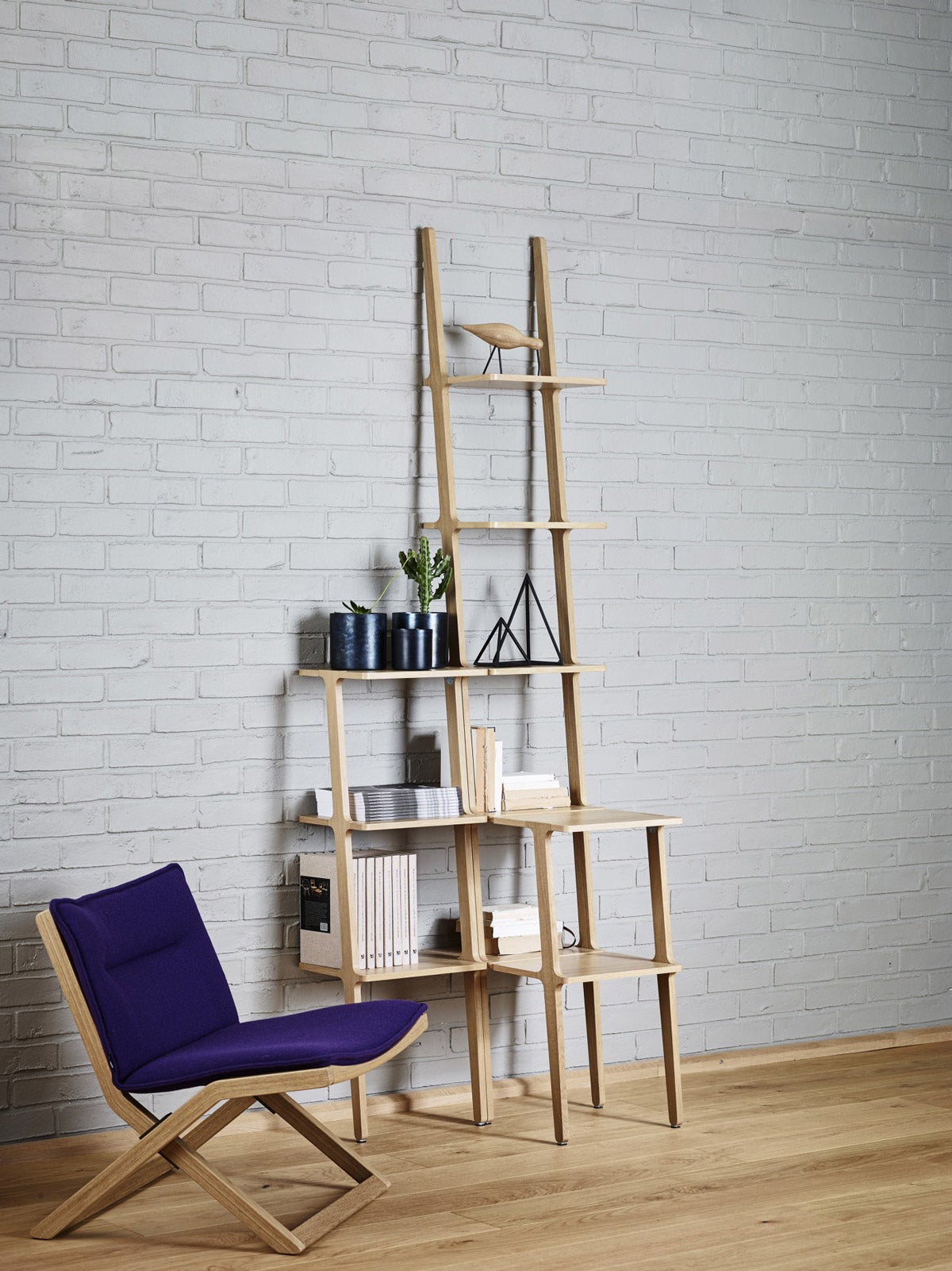 Libri hylla 5 hyllplan i ask ståendes mot en vitmålad tegelvägg.