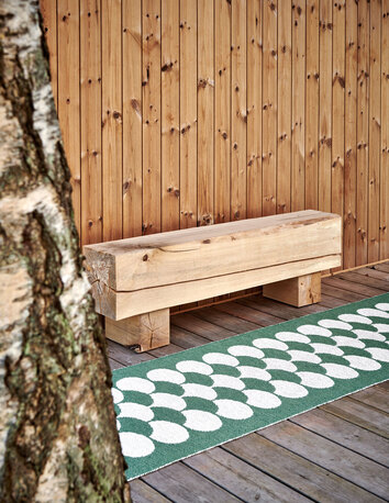 Poppy Gångmatta Oregano vid en uteplats på ett modernt trähus.